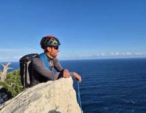 Grimpeur au sommet d'une longue voie en Sardaigne au dessus de la Méditerranée
